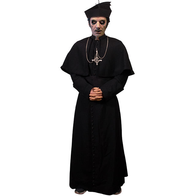 Man wearing all black costume. cassock, sash belt, cape, hat and silver necklace.