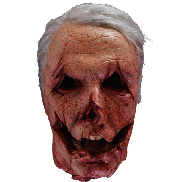Head prop, front view.  Decapitated head, gray hair. mutilated face with cuts around eyes, nose and mouth to give the appearance of a jack o' lantern.