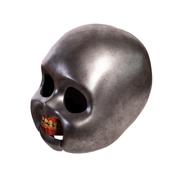 Left side view.  Good Guys doll skull prop. Metallic silver skull empty black eye sockets. Fleshy red gums with teeth.