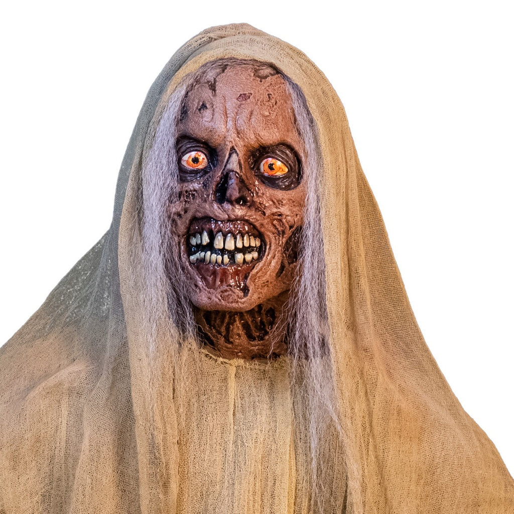 Close up detail of head, neck and shoulders of the Creep. Hanging prop.  White hair, rotting skin, yelllow eyes, gory grinning mouth with large teeth and gums. Wearing natural colored muslin veil and shirt. 