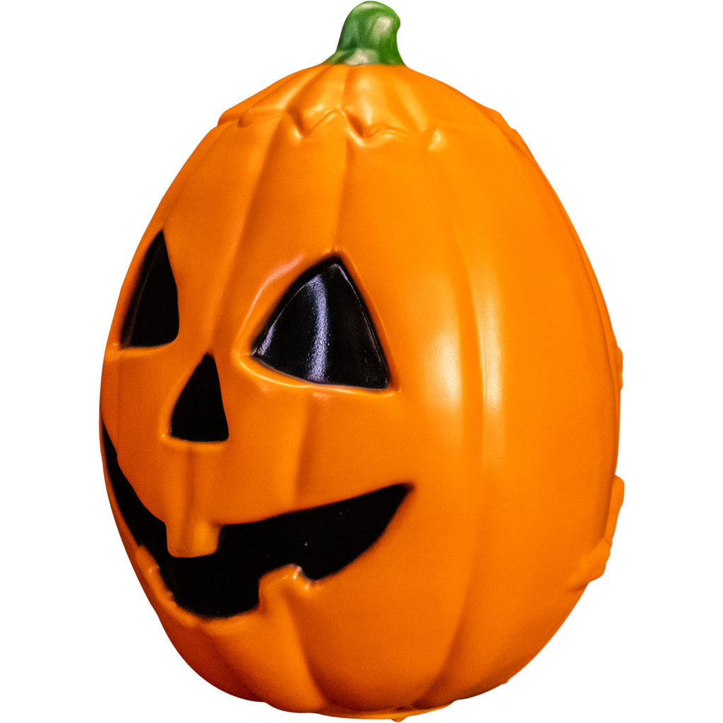 Pumpkin prop, left side view. Orange jack o' lantern, green stem, black triangle eyes and nose, grinning black mouth.