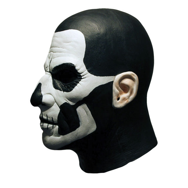 Mask, left side view. Head and neck. Bald, black painted head and neck, white painted face, with black accents to create skull like appearance.
