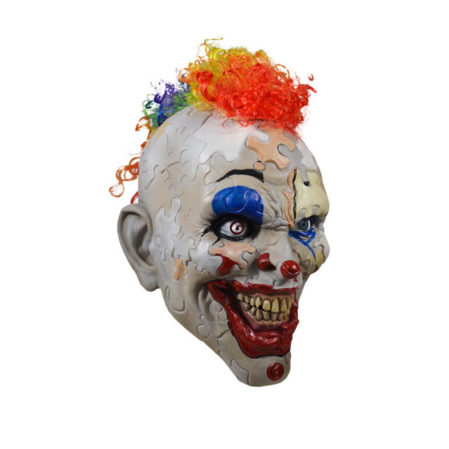 Right side view. Creepy clown face. Skin made up of puzzle pieces, gray, white, beige, and peach. Bright red clown mouth smiling with yellowed teeth. Spiral right eye. Rainbow curly mohawk hair.