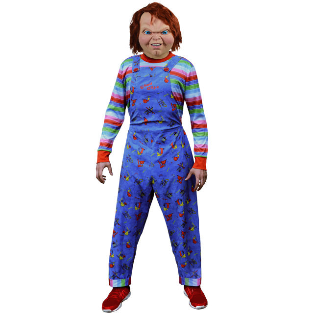 Person wearing Good Guys Chucky mask and Adult Good Guys costume.  Mask Has red hair blue eyes, menacing grin, cleft chin.  Wearing Green, red, white and blue striped shirt with red cuffs and collar, blue overalls with red buttons and Good Guys printed on front pocket.  Red shoes.