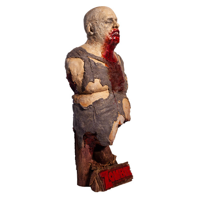 Bust right side view. Zombie, head and torso torn shirt, pot belly. Bald head, eyes closed, gory mouth blood from mouth running down chest. Base is wooden pier posts and rope. Plaque at bottom red text reads Zombie
