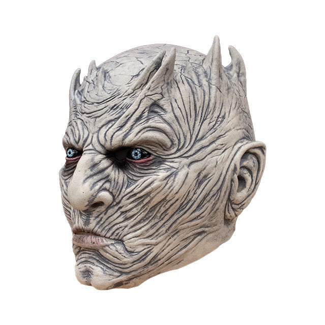 Left side view. Night King Mask. Bald head, extremely wrinkled light gray skin, spikes around crown of head. Bright blue red-rimmed eyes on black where the whites should be.