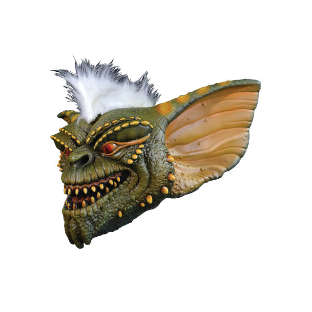 Mask left side view. Green and yellow Gremlin face, orange eyes sharp yellow teeth in grinning mouth, white furry stripe on head.