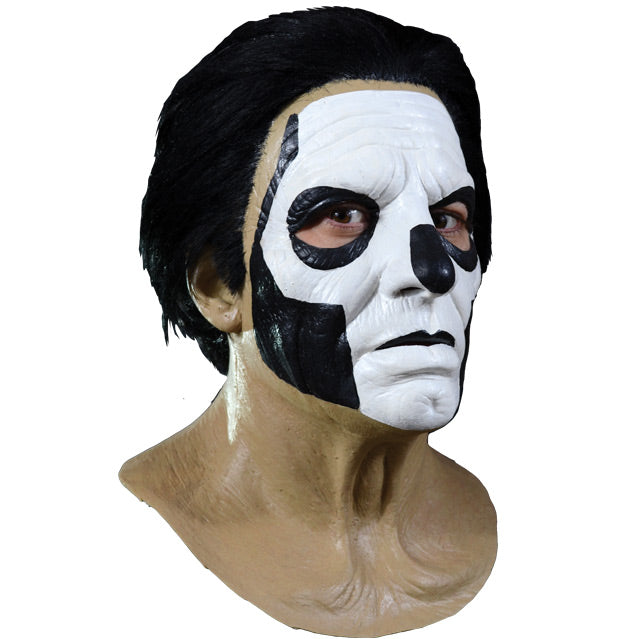 Mask, right side view. Head, neck and upper chest. Thick black hair, white painted face, with black accents to create skull like appearance.