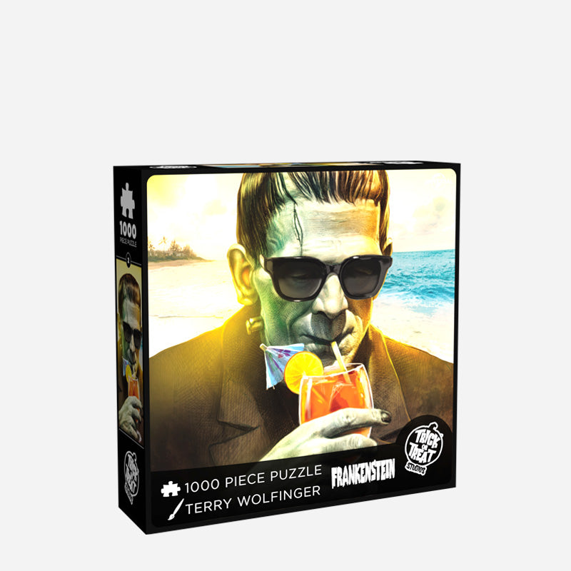  White background. Product packaging, box front. Illustration, Frankenstein on beach wearing sunglasses, drinking a tropical cocktail. White text on black border reads, 1000 piece puzzle, Terry Wolfinger, Frankenstein. White Trick or Treat studios logo bottom right.