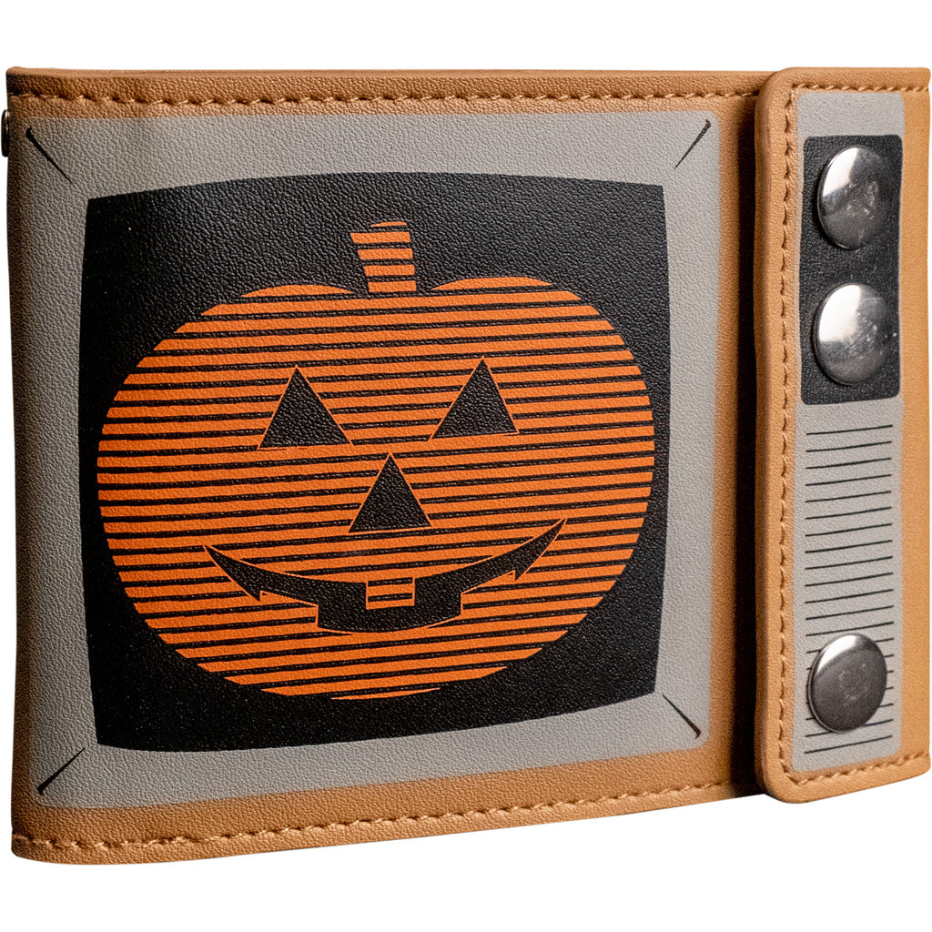 Magic Pumpkin TV wallet, close up front view, closed. Made to look like a vintage television. Tan background black and white details, screen shows orange jack o' lantern with horizontal black stripes on black background. Three silver snaps in place of TV knobs.