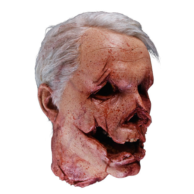 Head prop, right side view. Decapitated head, gray hair. mutilated face with cuts around eyes, nose and mouth to give the appearance of a jack o' lantern.
