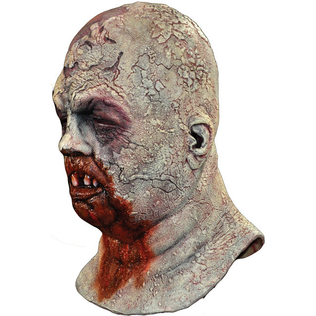 Mask left side view. Zombie, head and neck. Bald head, rotten skin, eyes closed, gory mouth missing teeth, blood from mouth running down chest.