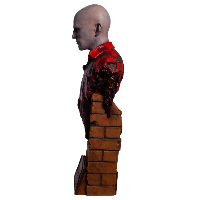 Left side view. Airport Zombie bust. Head shoulders and upper torso. Bald zombie, right side of face and chest is gory, wearing torn red and black flannel shirt, with gore hanging from left shoulder. Base of bust is a broken brick wall.
