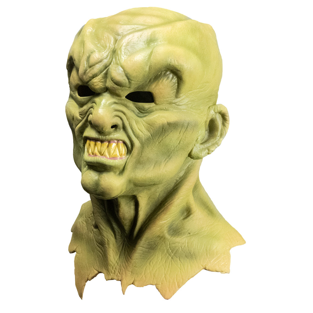 Mask, left side view. Head neck and upper chest. Greenish flesh, lumpy, misshapen bald head, Heavy brow over angry face, snarling mouth full of large sharp teeth.