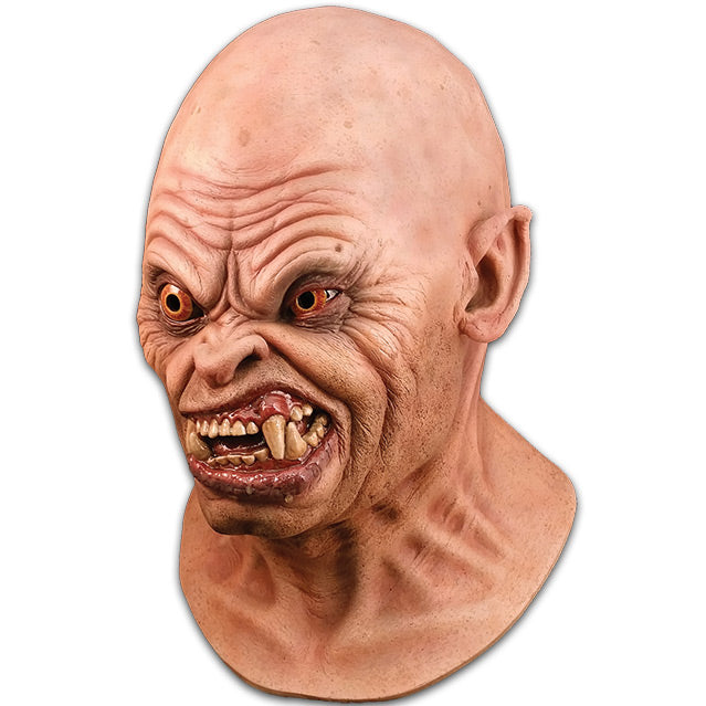 Left side view. Mask, head and neck. Bald head, slightly pointed ears. Creased skin on forehead, around eyes and mouth. Orange eyes, right eye bulging. Snarling mouth with crooked teeth and large fangs.