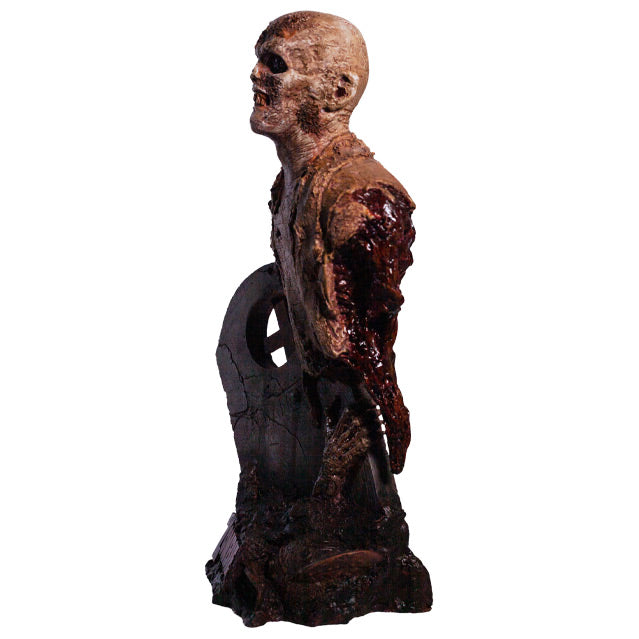 Bust, left side view. Rotted zombie head neck and upper torso, wearing dirty rotted torn clothing. Gore around shoulders, bottom of torso and back. Face has rotting flesh, black eyes, mouth of jagged dirty teeth. Base is gravestone set in soil, with zombie arm coming from the ground , plaque at bottom with red text reading Zombie.