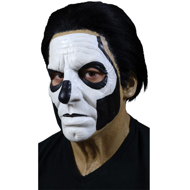 Mask, left side view. Head, neck and upper chest. Thick black hair, white painted face, with black accents to create skull like appearance.