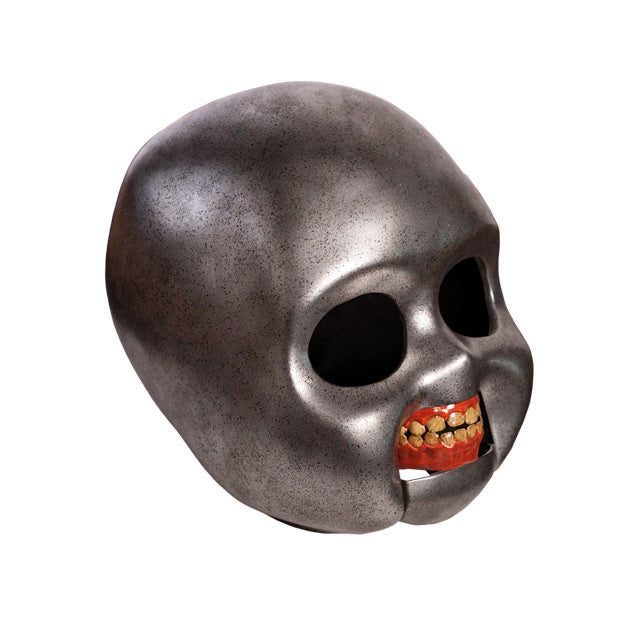 right side view. Good Guys doll skull prop. Metallic silver skull empty black eye sockets. Fleshy red gums with teeth.