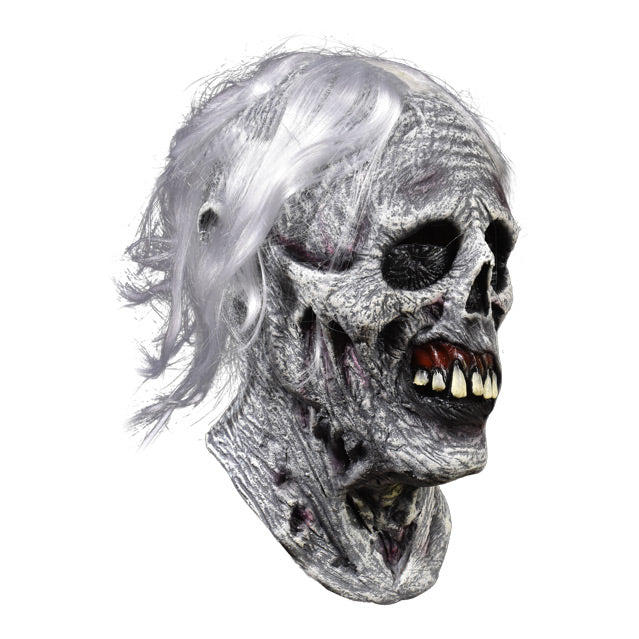 Right side view. Chiller mask. White and grey skeletal face with wrinkled and rotten flesh, black eye sockets, prominent teeth in dark red gums, bright white hair.