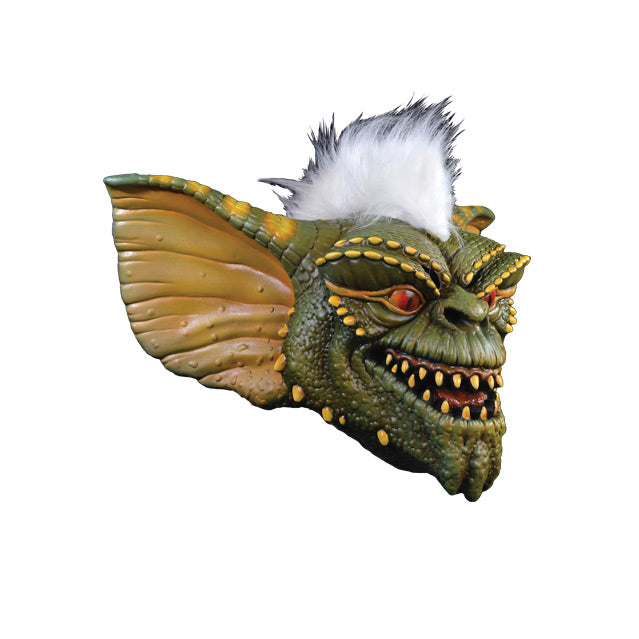 Mask right side view. Green and yellow Gremlin face, orange eyes sharp yellow teeth in grinning mouth, white furry stripe on head.