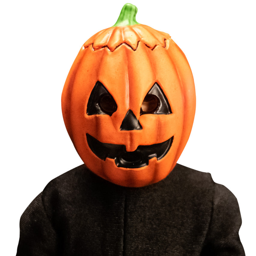 Close up of head and shoulders of jack o' lantern costume figure.  Orange jack o' lantern mask with black triangle eyes and nose, grinning black mouth.  wearing black shirt.