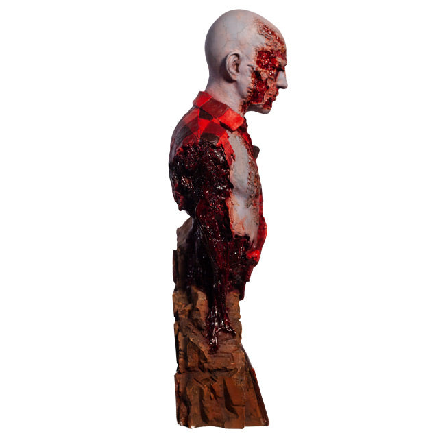 Right side  view. Airport Zombie bust. Head shoulders and upper torso. Bald zombie, right side of face and chest is gory, wearing torn red and black flannel shirt, with gore hanging from shoulder and back. Base of bust is a broken brick wall.