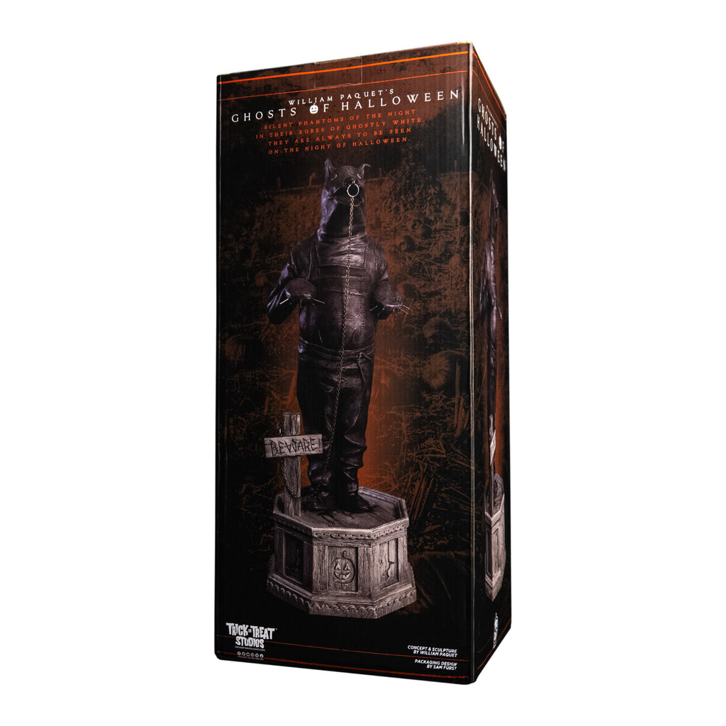 Product packaging, back of box. Front view, statue. Grayscale, Person in leather bondage bear costume, with metal claws on hands, ring in nose attached to chain that is attached to a cross, that says Beware, by his feet. Standing on hexagon base made of gravestones.  Manufactuing and licensing information.