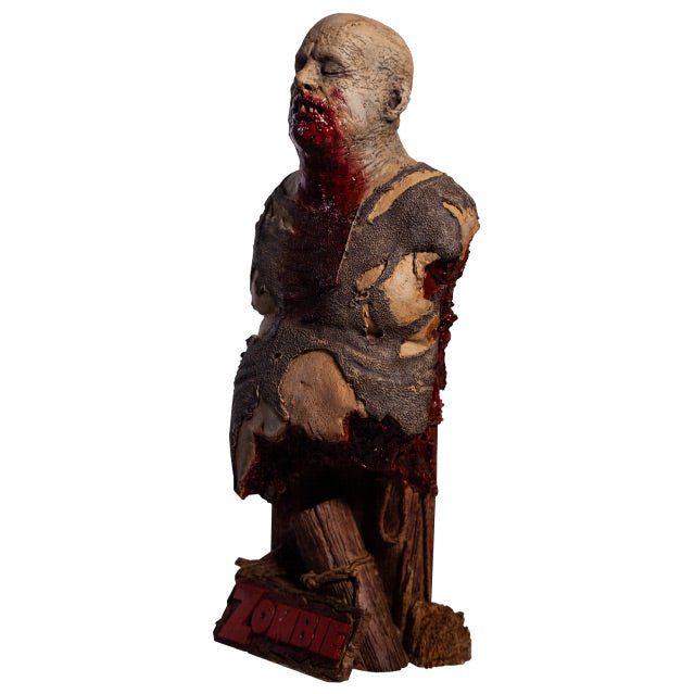 Bust left side view. Zombie, head and torso torn shirt, pot belly. Bald head, eyes closed, gory mouth blood from mouth running down chest, back is gory and bloody. Base is wooden pier posts and rope. Plaque at bottom red text reads Zombie