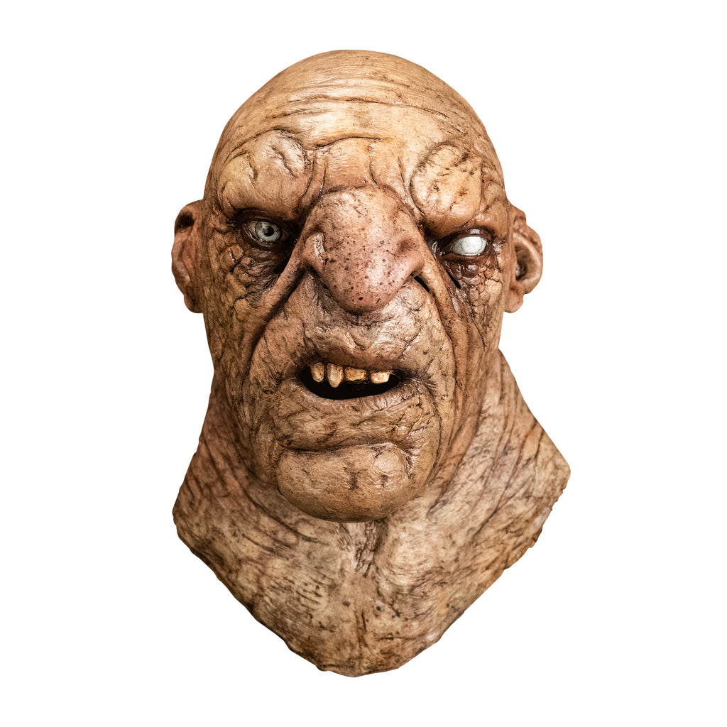 Mask, head and neck, front view. Troll, bald, wrinkled and dirty tan skin, large nose and chin, mouth open showing teeth.  Small ears, right eye blue, left eye white. Thick neck.