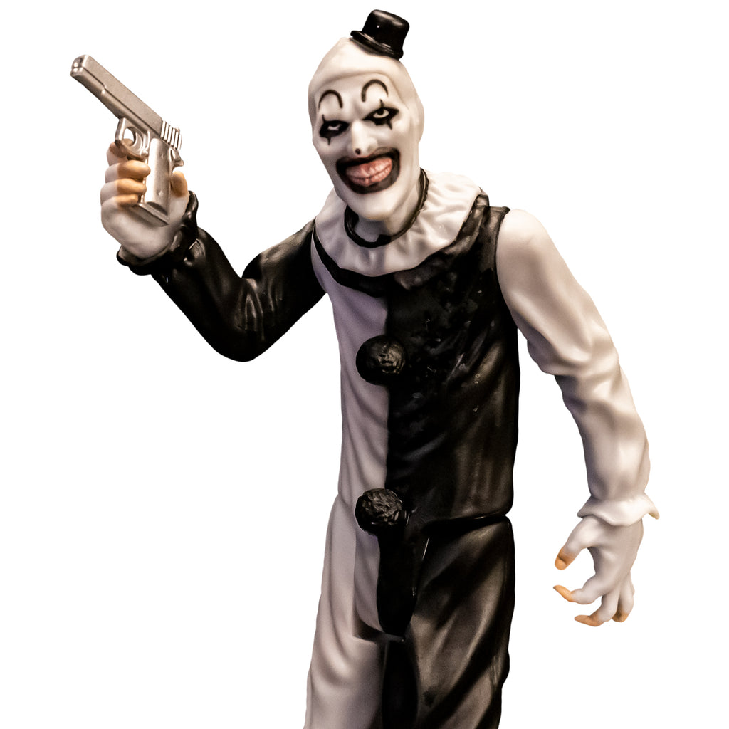 Terrifier, 5 inch figure, close up. Evil grinning clown face with tiny black top hat, black and white, jumpsuit, ruffle at neck, fingerless white gloves holding silver pistol in right hand.