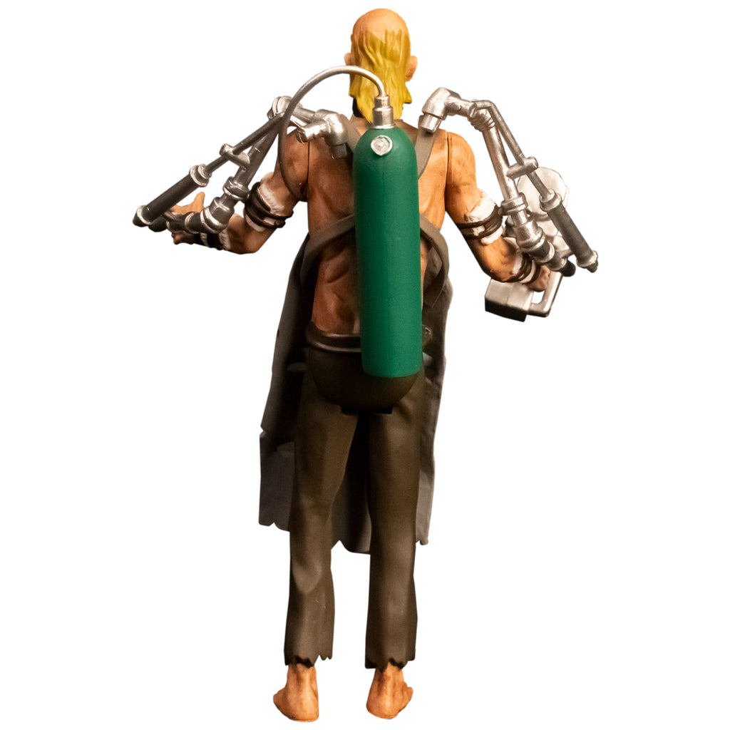 Action figure, back view. Bald man, long blond hair on back of head, wearing green oxygen tank on back, black, gray apron, shirtless, brown tattered pants, bare feet. Silver drill tools attached to both arms with black straps.