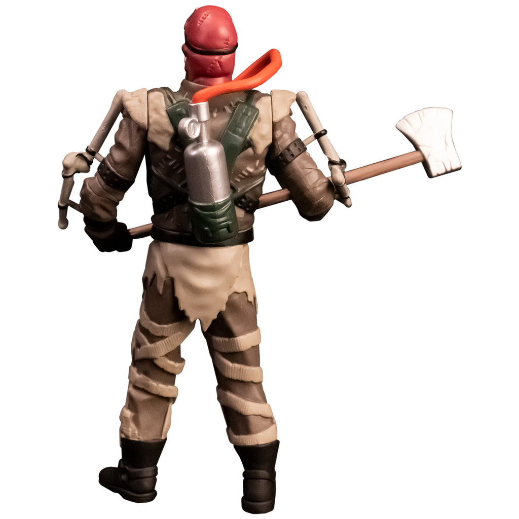 Action figure. Back view. Person with red head, silver oxygen tank on back with orange hose. Tattered brown and tan outfit, apparatus attached to arms, ammunition belts across chest, black gloves and boots. Holding large Axe.