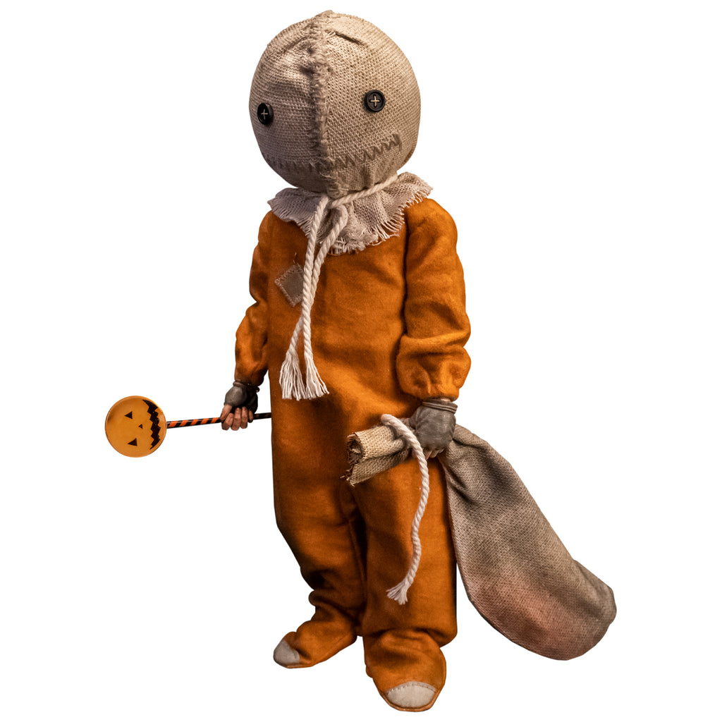Trick 'r Treat Sam 1/6 scale figure. Head is a stitched burlap sack, Button eyes, stitched mouth, rope tied around neck. wearing orange footy pajamas, brown fingerless gloves. Holding lollipop in right hand, burlap sack in. left hand.