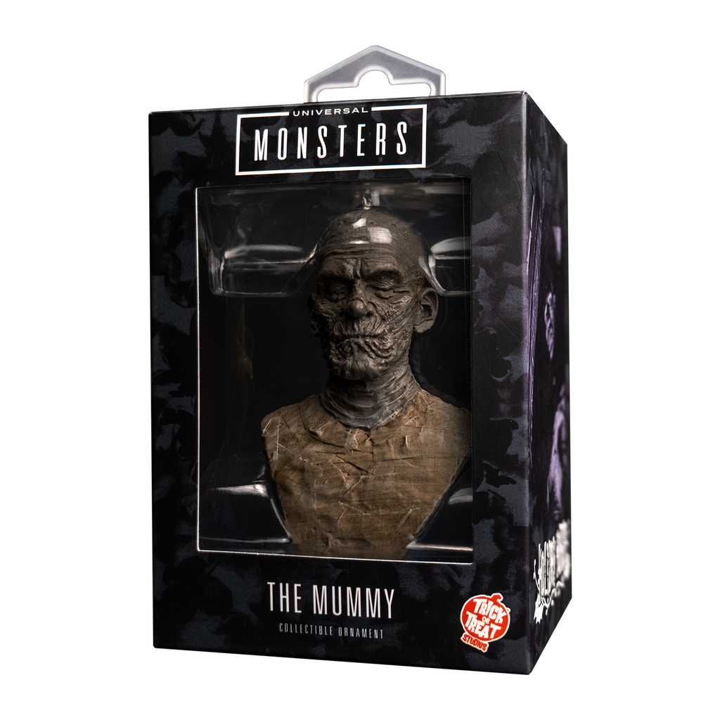 Product packaging, front.  Black window box showing ornament.  Text reads Universal Monsters, the Mummy, collectible ornament.  Orange and white Trick or Treat Studios logo.