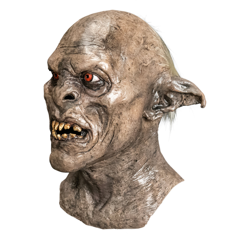 Mask, head, neck and upper chest, left side view. Orc, wrinkled gray-brown dirty skin, tattered pointed ears, snarling mouth with dirty sharp teeth. Red-orange eyes. White tuft of hair behind ear.