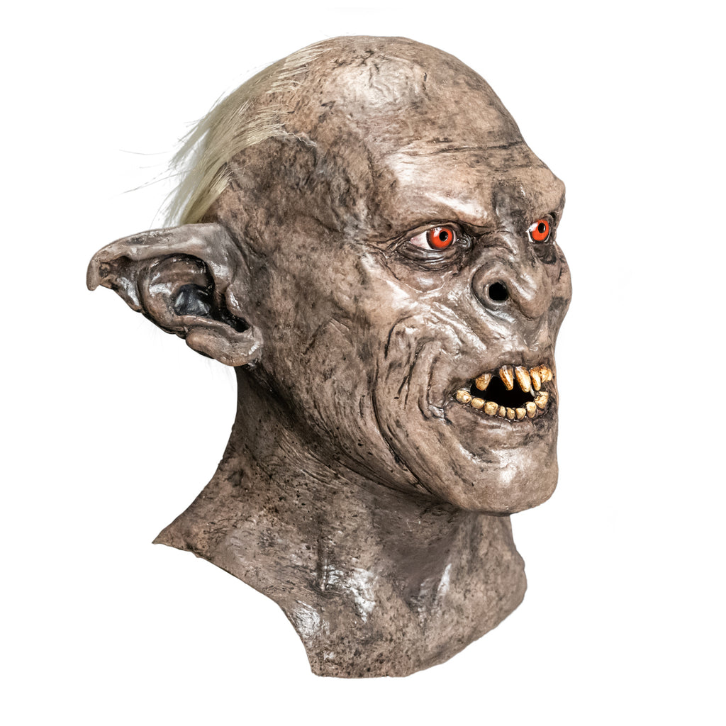 Mask, head, neck and upper chest, right side view. Orc, wrinkled gray-brown dirty skin, tattered pointed ears, snarling mouth with dirty sharp teeth. Red-orange eyes. White tufts of hair on back of head.