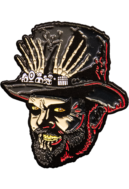 Enamel pin.  Head of man, Dr. Death.  Wearing tall black hat, decorated with small skulls and skeleton hands. Pale flesh tone face has orange eyes, thick black eyeliner, menacing smile with yellow teeth, black full beard.  Red highlights around edges.