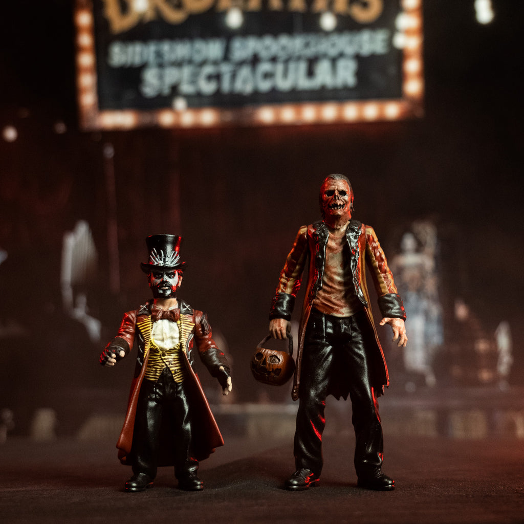 Candy Corn action figures. Left, Dr. Death, Small man, black top hat, white face, full beard. wearing long red and black coat, white shirt, yellow and black striped vest, red bowtie, black pants, black boots, black fingerless gloves. Right, tall man with gory orange Jack O' Lantern-like face. Wearing a blood-stained shirt, red and orange striped coat with black cuffs and sleeves, black pants, black boots. Holding orange jack o' lantern candy pail.   Both in front of a blurred, dark, circus-like background