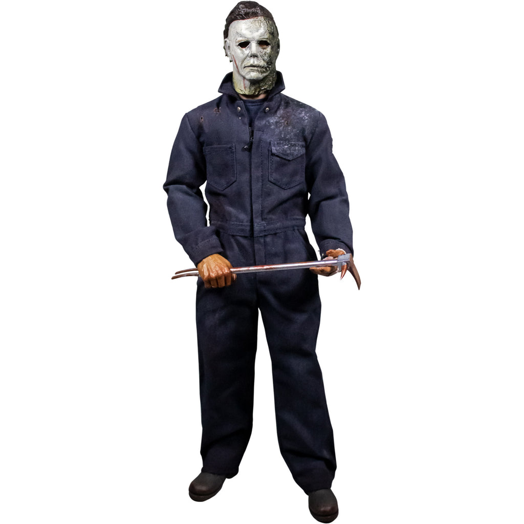 Front view, Michael Myers 12 inch action figure. Wearing Halloween kills mask, blue coveralls, black boots. Holding bloody breaching tool in front with both hands.
