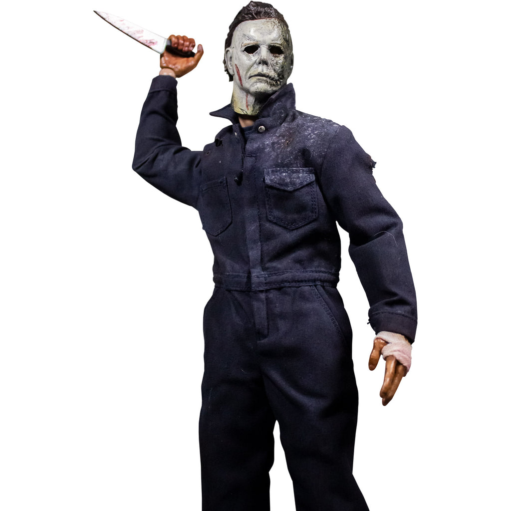 Front view, Michael Myers 12 inch action figure. Wearing Halloween kills mask, blue coveralls. Wielding butcher knife in left hand in aggressive stance.  Bandaged left hand.