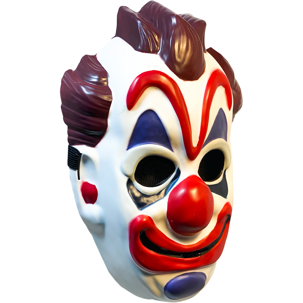Plastic mask, right view. White clown face, brown hair on top and sides of head. Exaggerated red eyebrows, nose, and smiling mouth. Blue above and below eyes and on chin