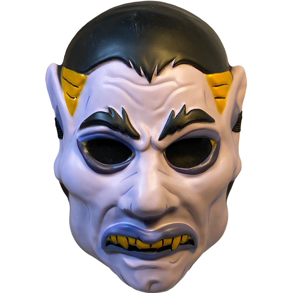 Plastic mask, front view. White vampire face. Black hair, eyebrows and eyes. Blue-gray eyeliner and lips. Frowning mouth with yellow teeth and fangs. Yellow at temples. Pointed ears. 