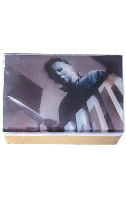 Bar soap. black and white illustration of Halloween movie scene, Michael Myers holding a kitchen knife peering over a banister. under clear soap layer. 