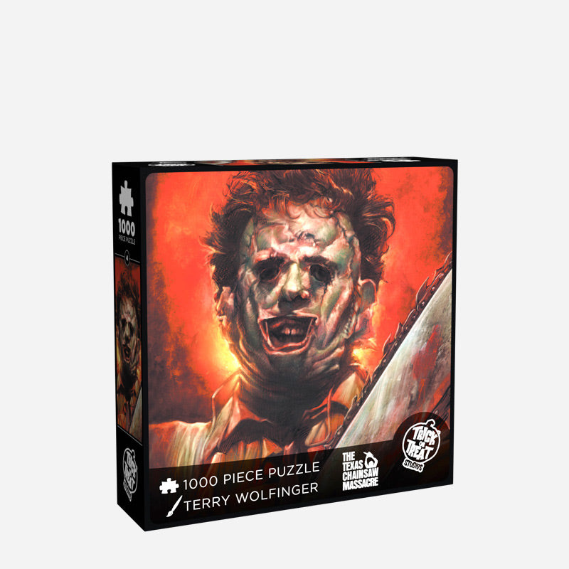 Leatherface jigsaw puzzle box cover. Showing Leatherface holding chainsaw, wearing patchwork flesh mask, on orange background. Text reads 1000 piece puzzle, Terry Wolfinger, The Texas Chainsaw Massacre. White Trick or Treat Studios logo.