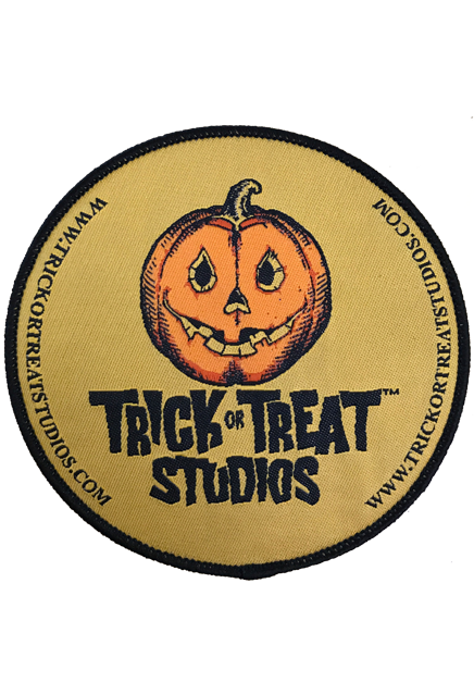 Patch. Tan circle, black border.  Black text on both sides reads www.trickortreatstudios.com.  Orange yellow and black Jack o' lantern with smiling mouth, above black text that reads Trick or Treat Studios. 