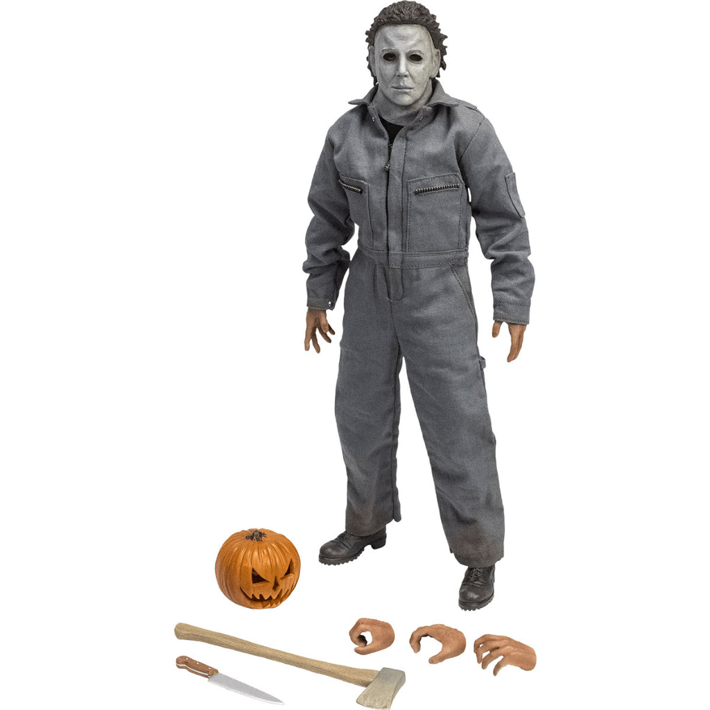 Front view. Halloween 6 Michael Myers 12" figure. White mask brown hair, wearing coveralls, black boots. Additional accessories at feet, jack o' lantern, 2 additional right hands, one additional left hand, Axe and kitchen knife.