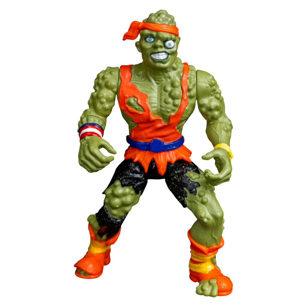 Toxie action figure, front view.  Green, lumpy, muscular humanoid figure.  Bald, green lumpy blistered flesh, with bright orange headband tied around forehead. Misaligned blue eyes, crooked nose. Lips open showing large teeth. Wearing tattered orange tank top, blue belt, tattered black pants, orange and yellow battered boots.  red white and blue wrist band on right wrist, yellow wristband on left wrist.